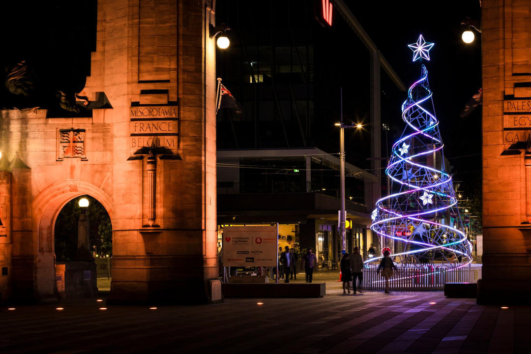 Spiral-lit Christmas tree between stone arches at night