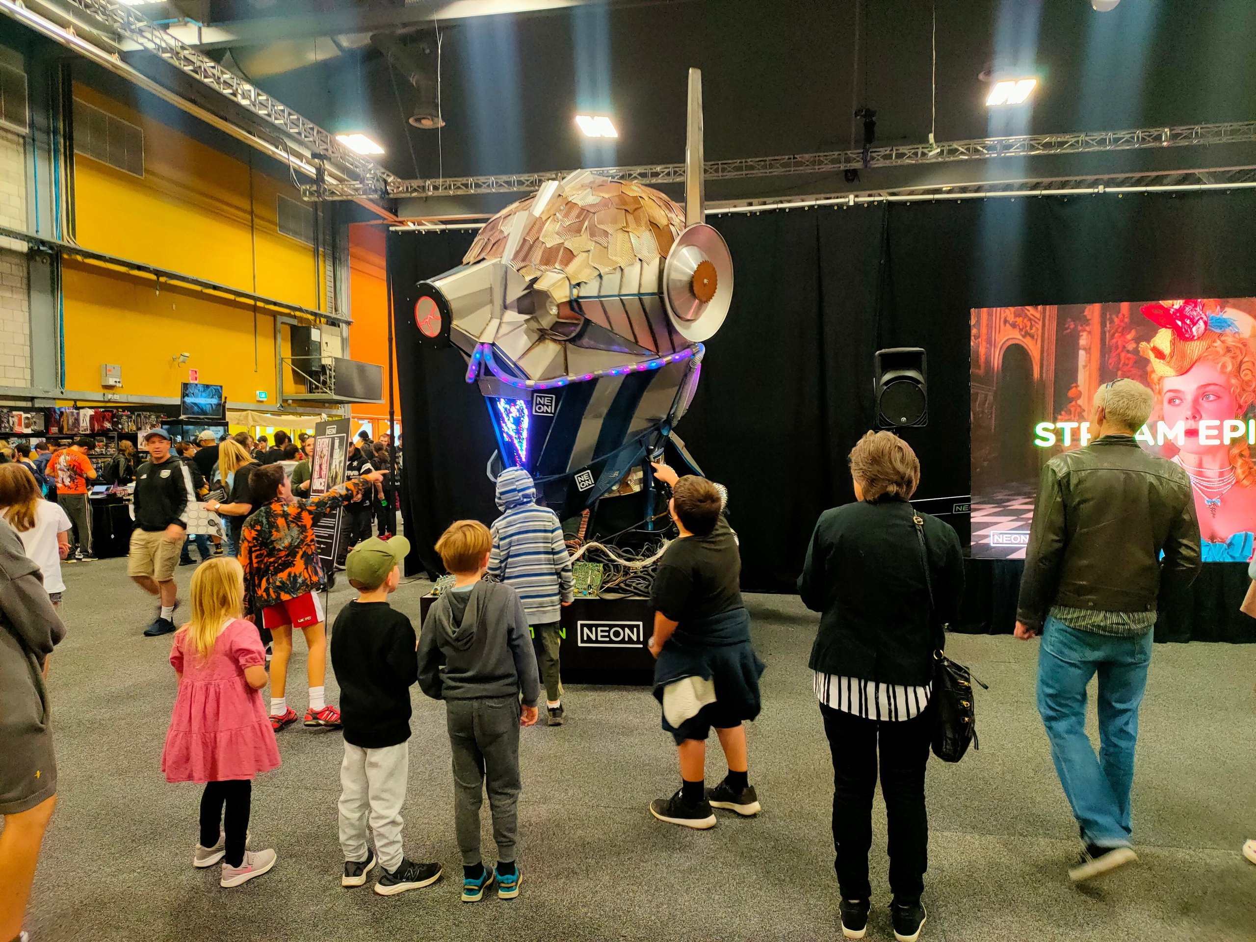 Crowd gathered around a glowing spaceship installation at an indoor expo