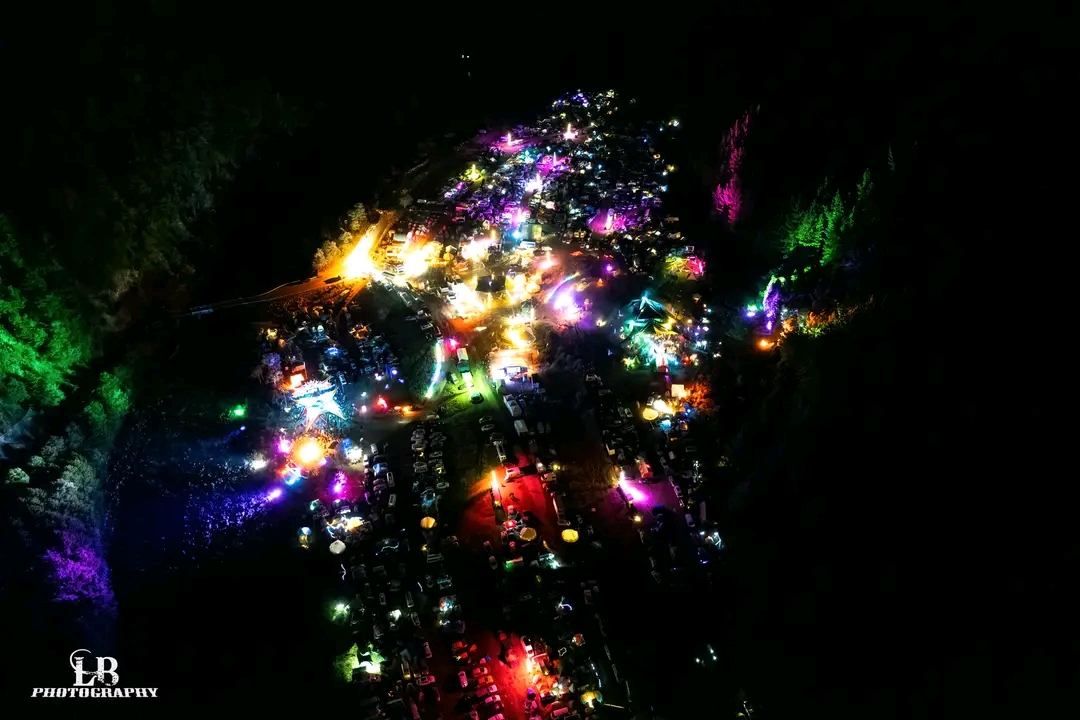 Glowing stick-figure light sculptures walking among a night crowd