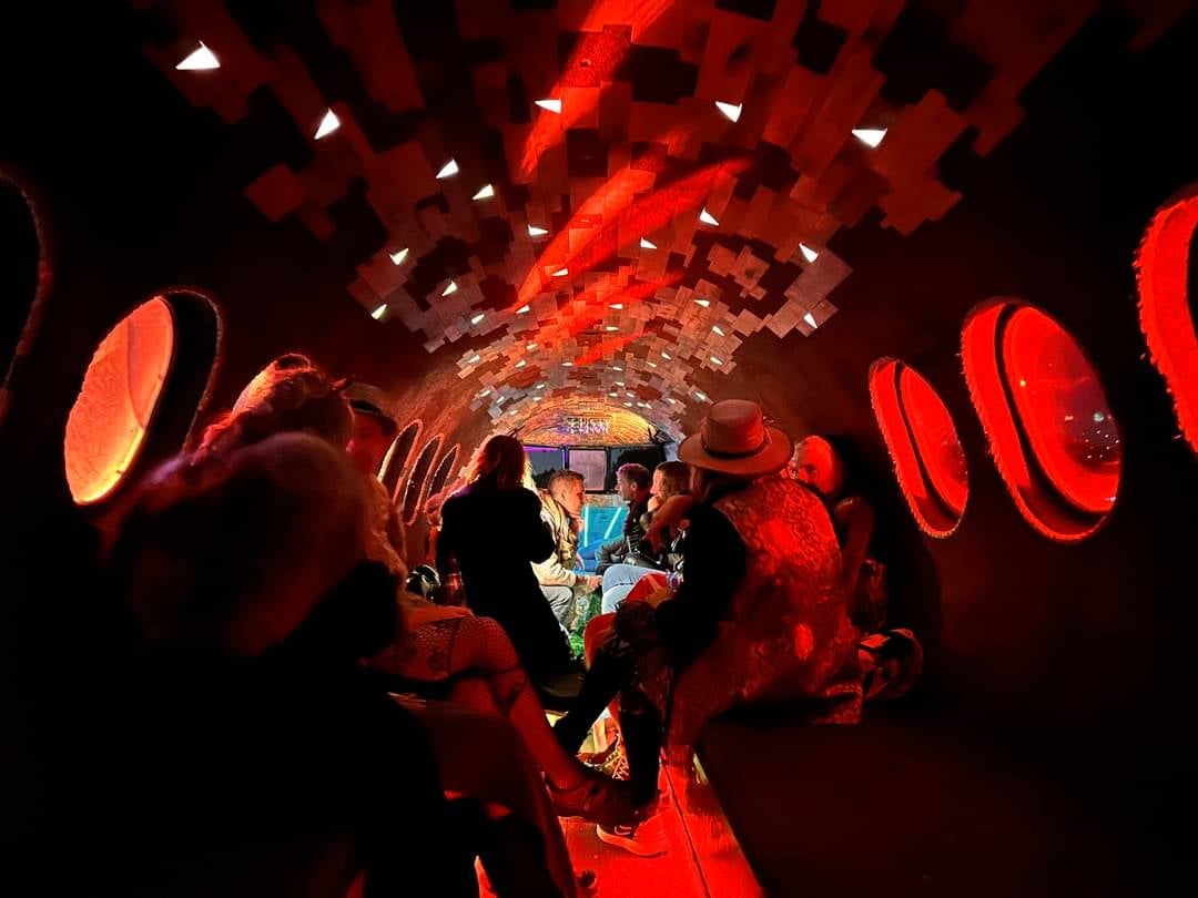 People inside a red-lit art tunnel installation
